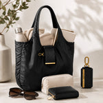 Bolsa Bijou negra abierta con botella, suéter y cartera, junto a su estuche llavero