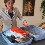 Una viajera acomoda su ropa en las bolsas de viaje y las comprime dentro de su maleta